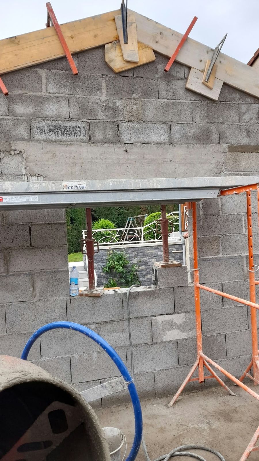 Ouverture dans un mur en parpaing, soutenue par des étais pendant la pose du linteau