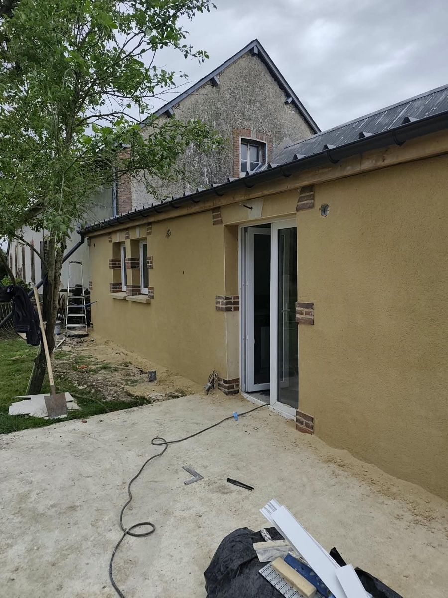 Après travaux : terrasse en béton le long de la maison et façade enduite