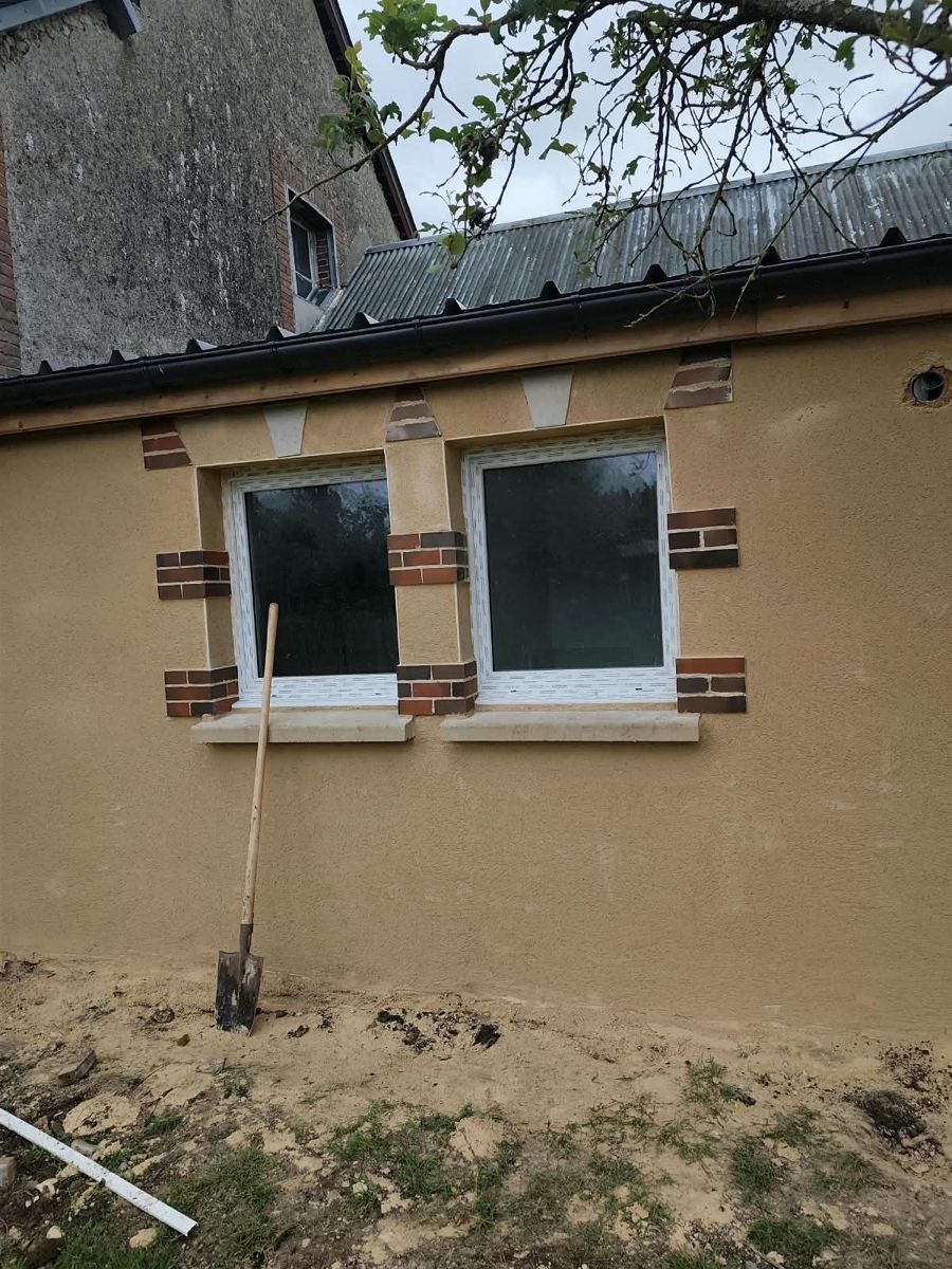 Après travaux : façade enduite avec encadrements de fenêtres en brique