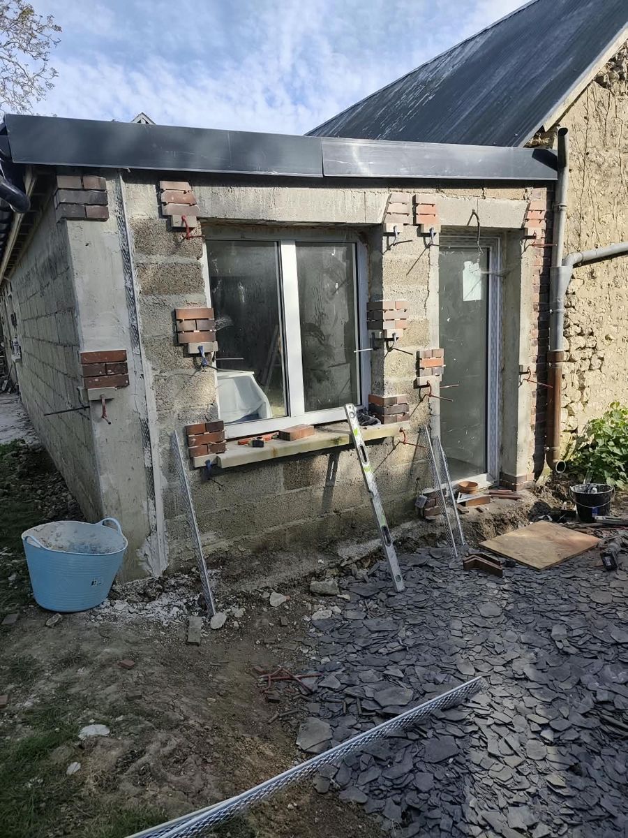 Avant travaux : sol en terre et mur brut le long de la maison