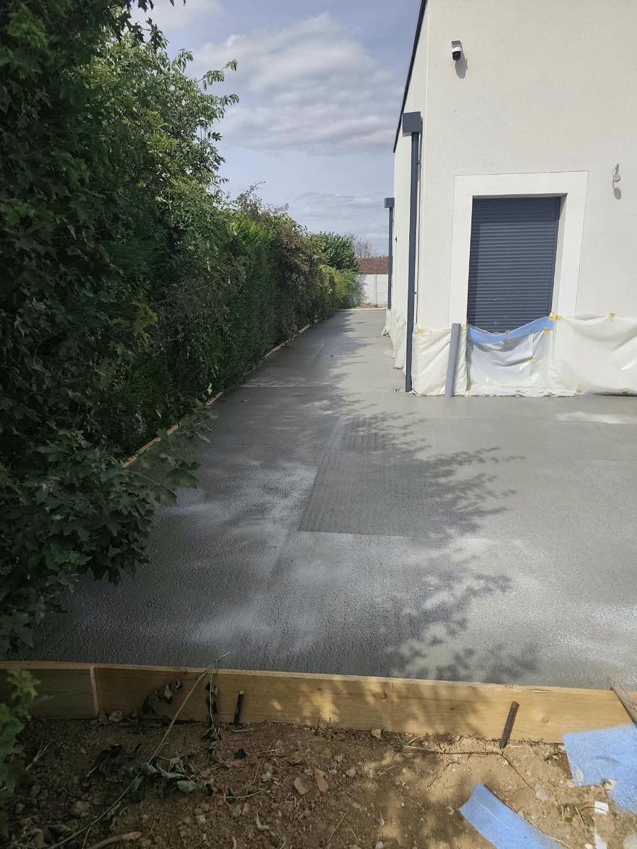 Allée en béton longeant la maison et la haie