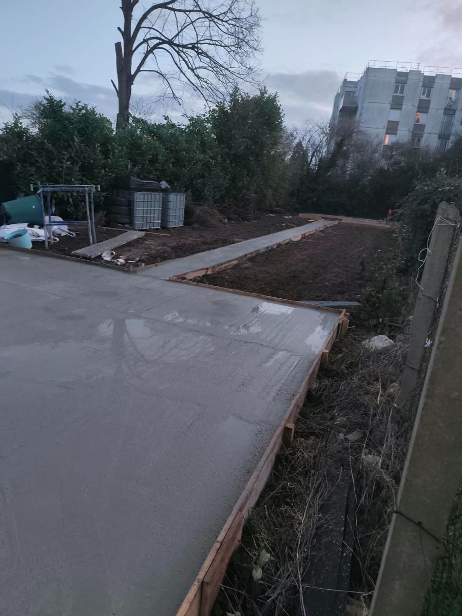 Dalle en béton fraîchement coulée et allée en béton traversant le jardin, coffrages bois